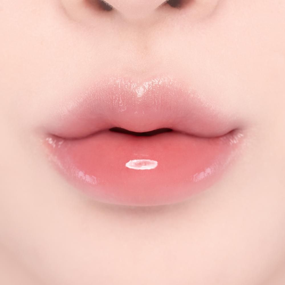 Gros plan sur des lèvres pleines et roses avec un gloss brillant et un reflet blanc.