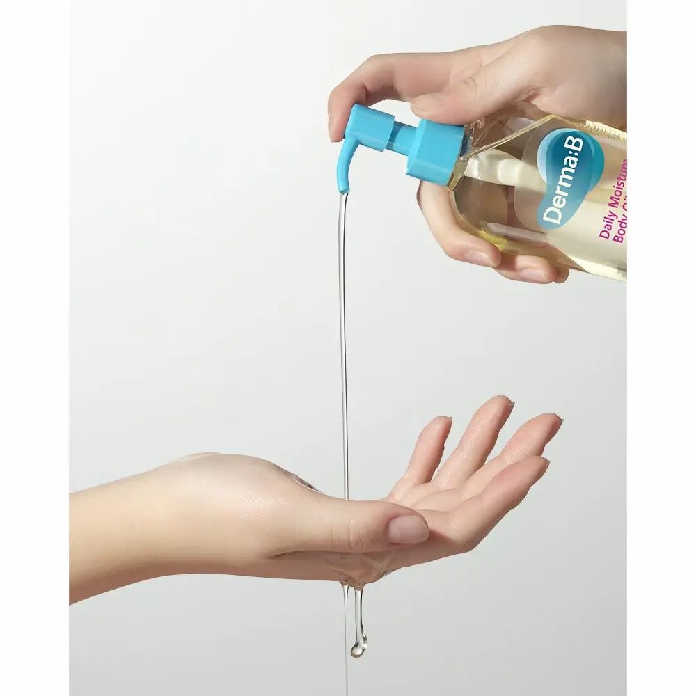 Handen houden body oil fles. Olie wordt in de hand gegoten. Opschrift: Derma:B, Daily Moisture Body Oil.
