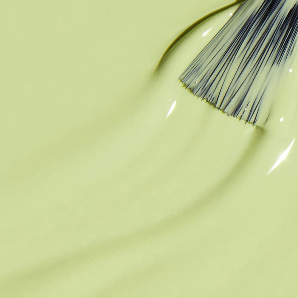 Vernis à ongles vert clair avec pinceau. Le pinceau est plongé dans le vernis, créant une surface lisse et brillante.