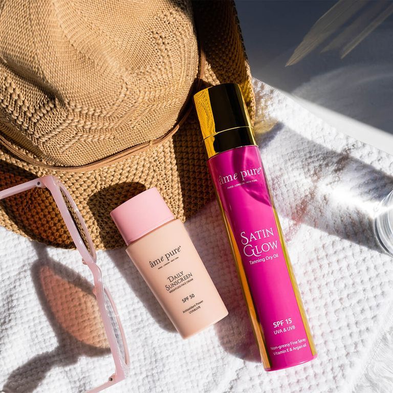 Âme Pure Daily Sunscreen SPF 50 et Satin Glow Tanning Dry Oil sur une serviette.