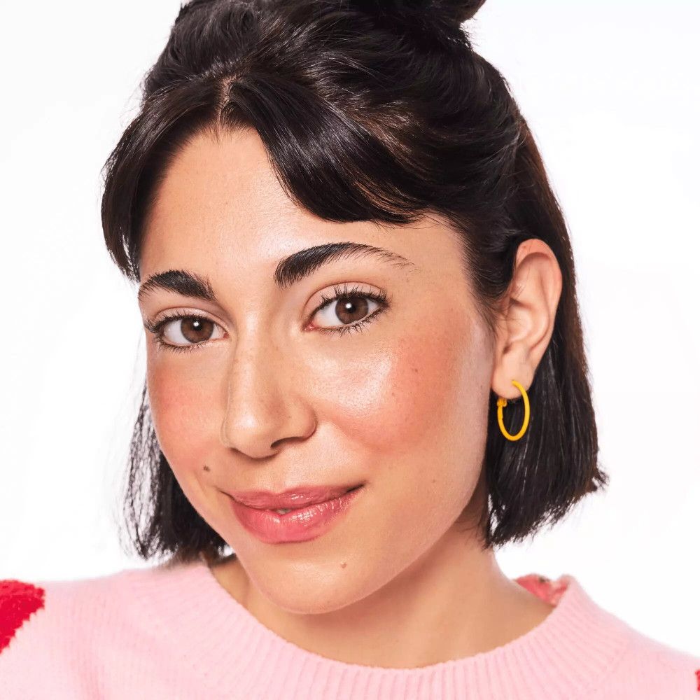 Portrait d'une femme avec peau bronzée et boucles d'oreilles jaunes.