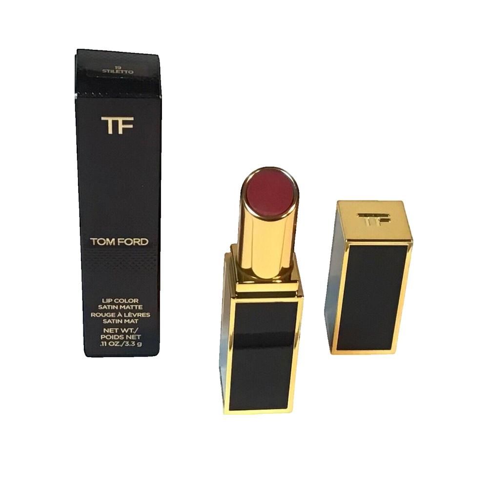 Rouge à lèvres Tom Ford, boîtier doré, emballage noir. Ouvert, capuchon à côté. Inscription: Tom Ford.