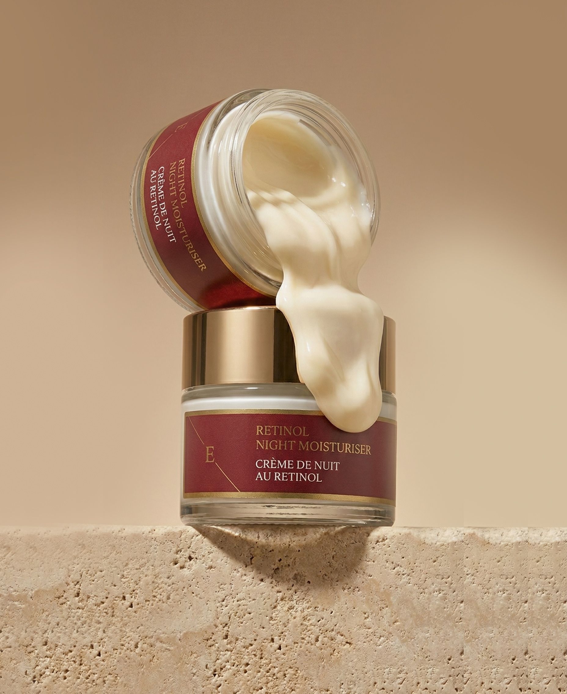 Twee crèmepotten, één geopend, crème stroomt eruit. Tekst: Retinol Night Moisturiser, Crème de Nuit au Rétinol.
