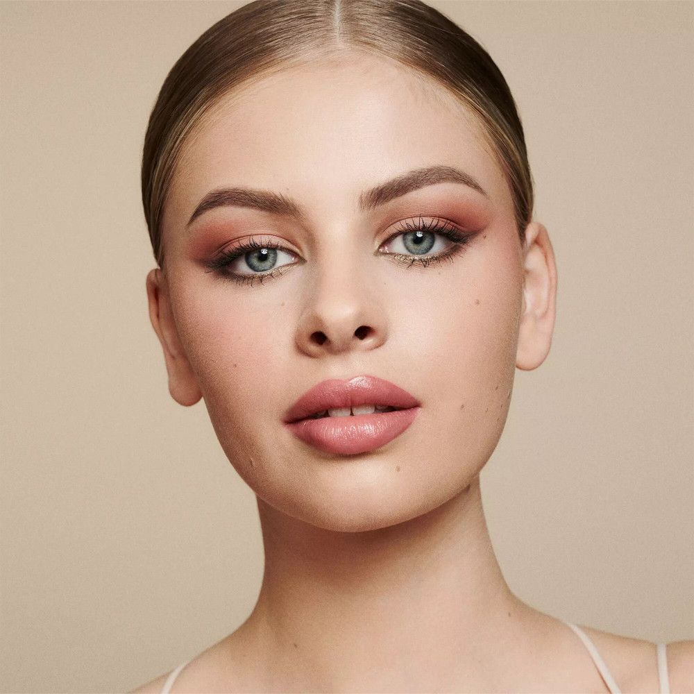 Portrait d'une femme maquillée. Accent sur les yeux et les lèvres. Fond beige.