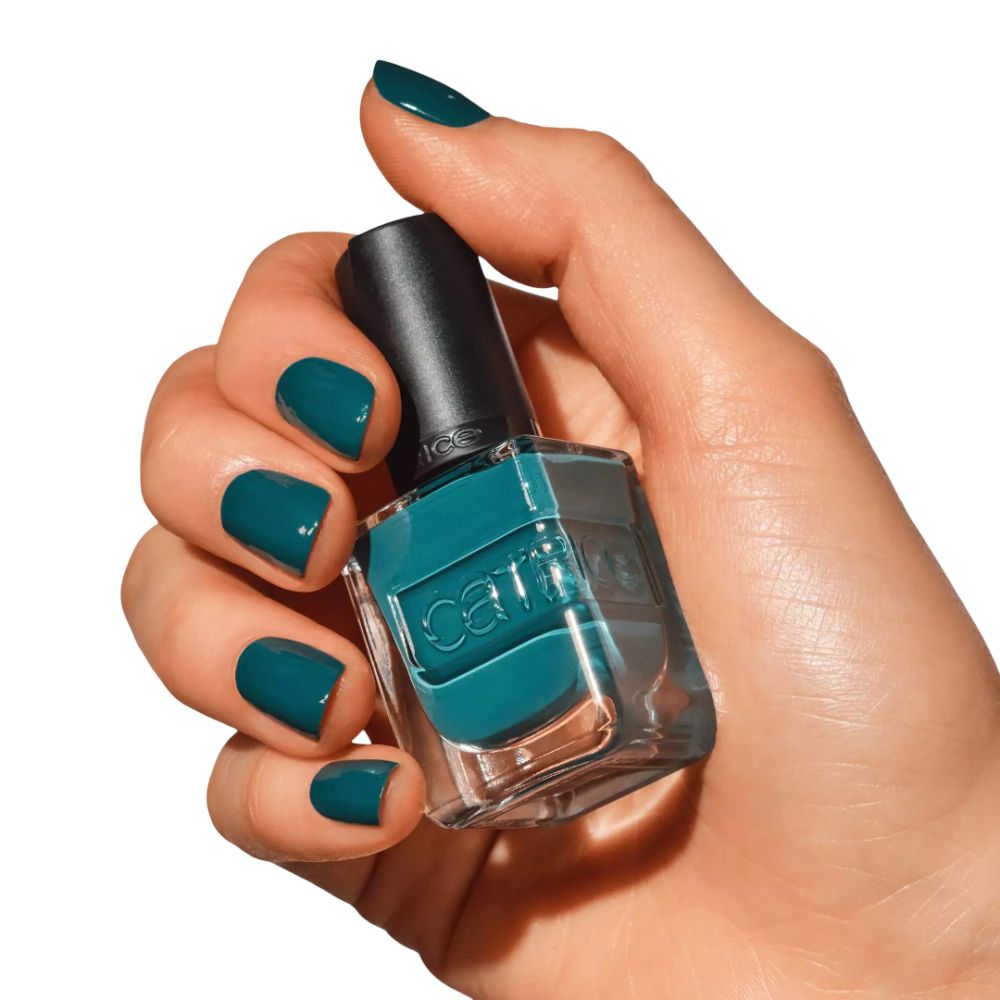 Main tenant un flacon de vernis à ongles. Ongles vernis en vert. Marque Catrice visible.