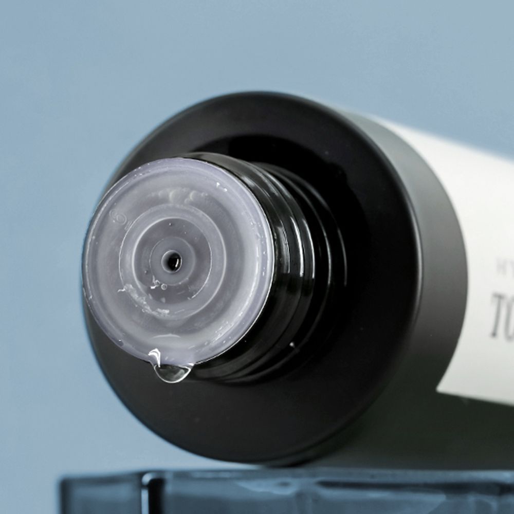 Gros plan sur le goulot de la bouteille. Bouchon noir avec fermeture transparente. Une goutte de liquide.