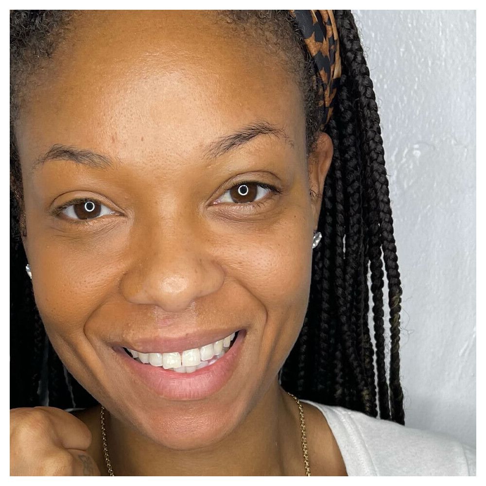 Portrait d'une femme souriante avec des tresses et un bandeau. Teint: bronzé. Yeux: marron.