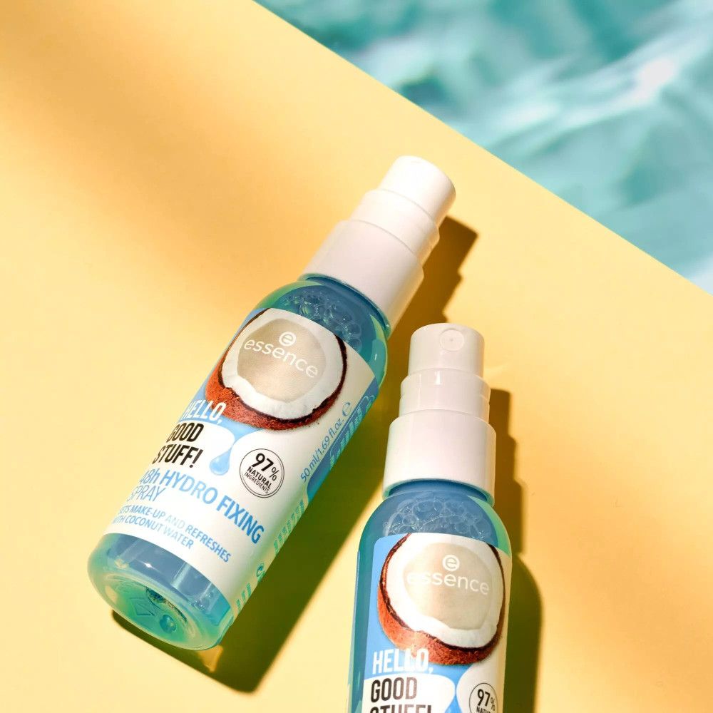 Twee sprayflessen op gele achtergrond. Opschrift: Hello Good Stuff, 48h Hydro Fixing Spray. Met kokoswater. Achtergrond: water.