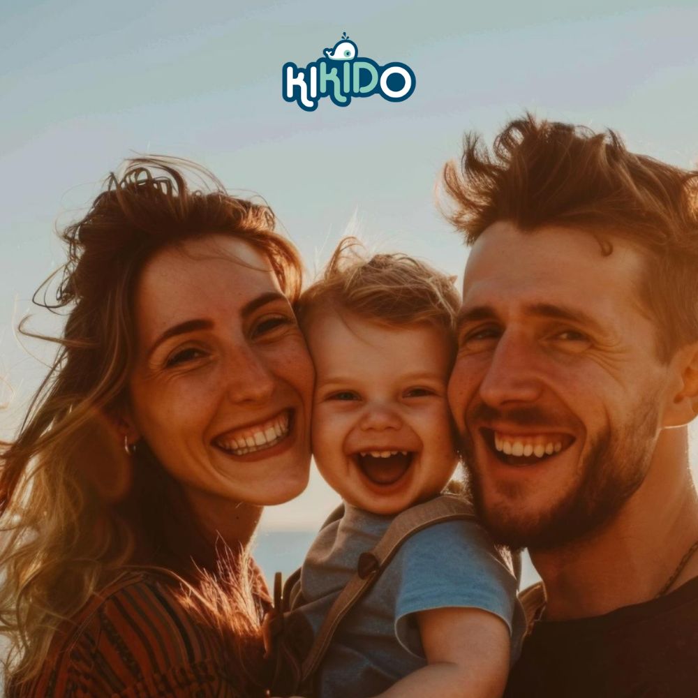 Familiefoto: ouders met baby. Iedereen lacht. Fel zonlicht. Kikido logo rechtsboven.