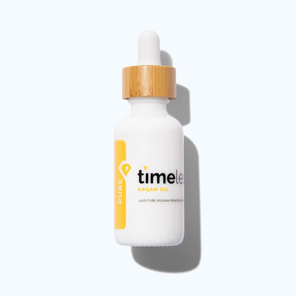 Witte fles met houten dop en pipet. Geel etiket met "PURE" en "timeless ARGAN OIL".