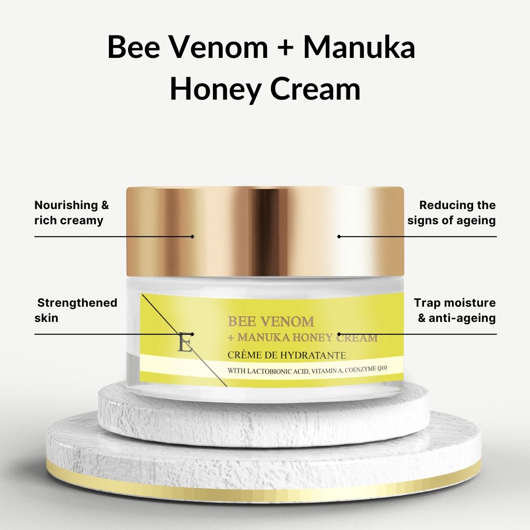 Pot de crème avec couvercle doré. Étiquette jaune avec texte: Bee Venom + Manuka Honey Cream. Sur socle.