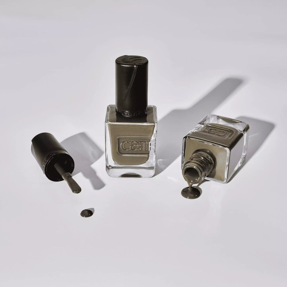 Deux flacons de vernis à ongles et un pinceau sur fond blanc. Un flacon est couché.