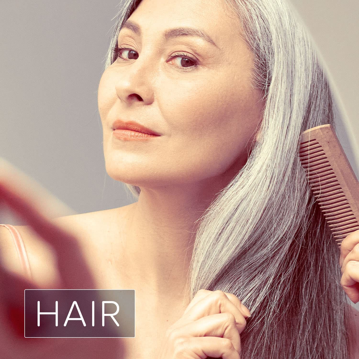 Vrouw met grijs haar kamt zich. Tekst: HAIR.