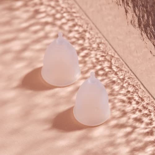 Deux coupes menstruelles transparentes sur fond rose. Elles ont une forme ronde avec une tige.