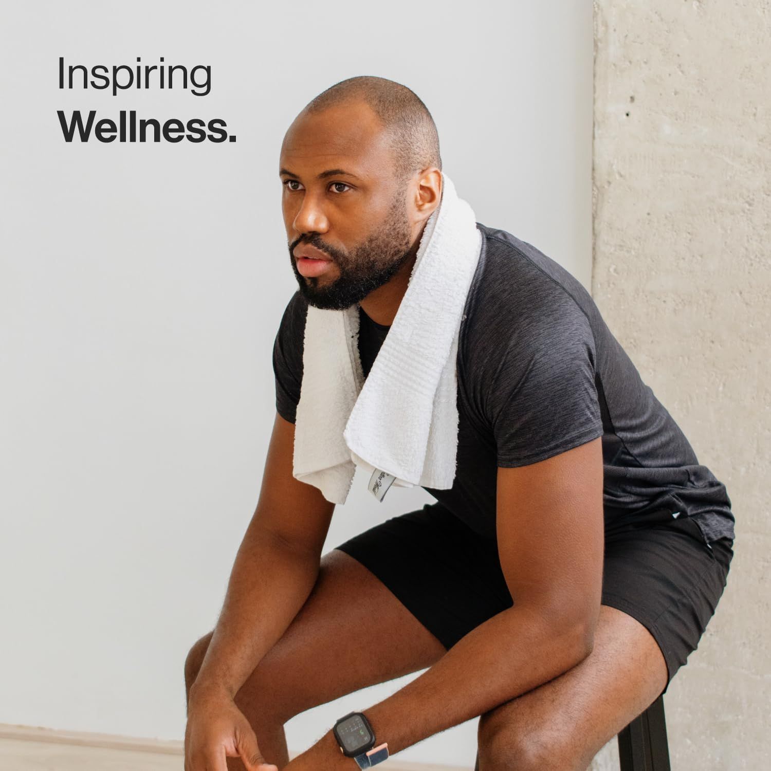 Man met handdoek om de nek, zittend. Tekst: Inspiring Wellness.