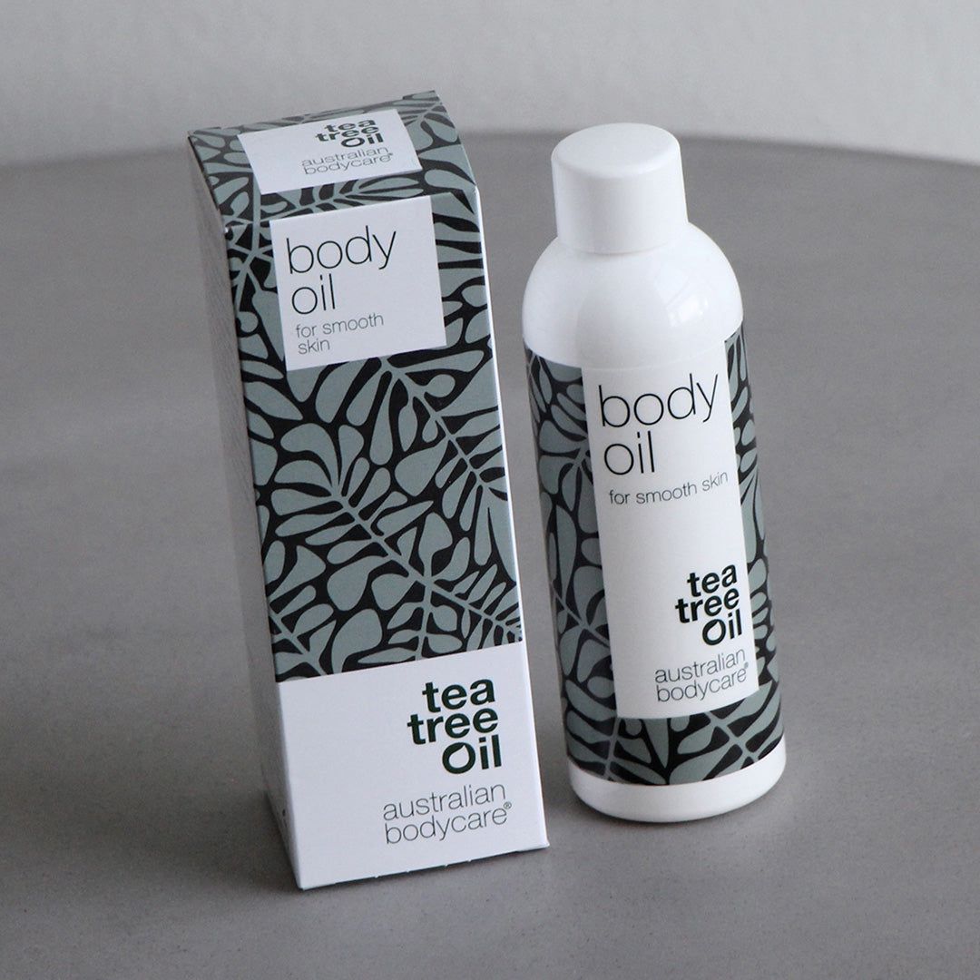 Body Oil fles en verpakking. Witte fles en doos met grijze bladeren. Tekst: Tea Tree Oil, Australian Bodycare.