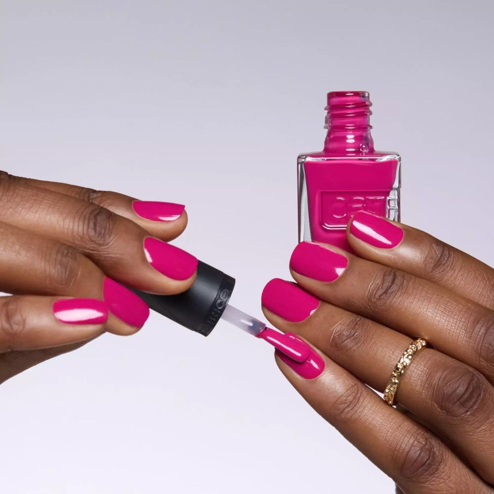 Mains appliquant du vernis à ongles rose. Flacon de vernis à ongles avec pinceau. Bouchon noir avec inscription "catrice".