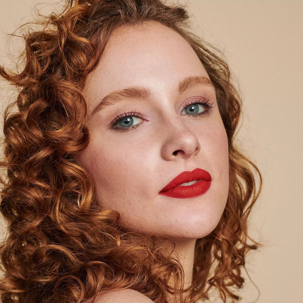 Portret van een vrouw met rode lippen. Rood haar, blauwe ogen.