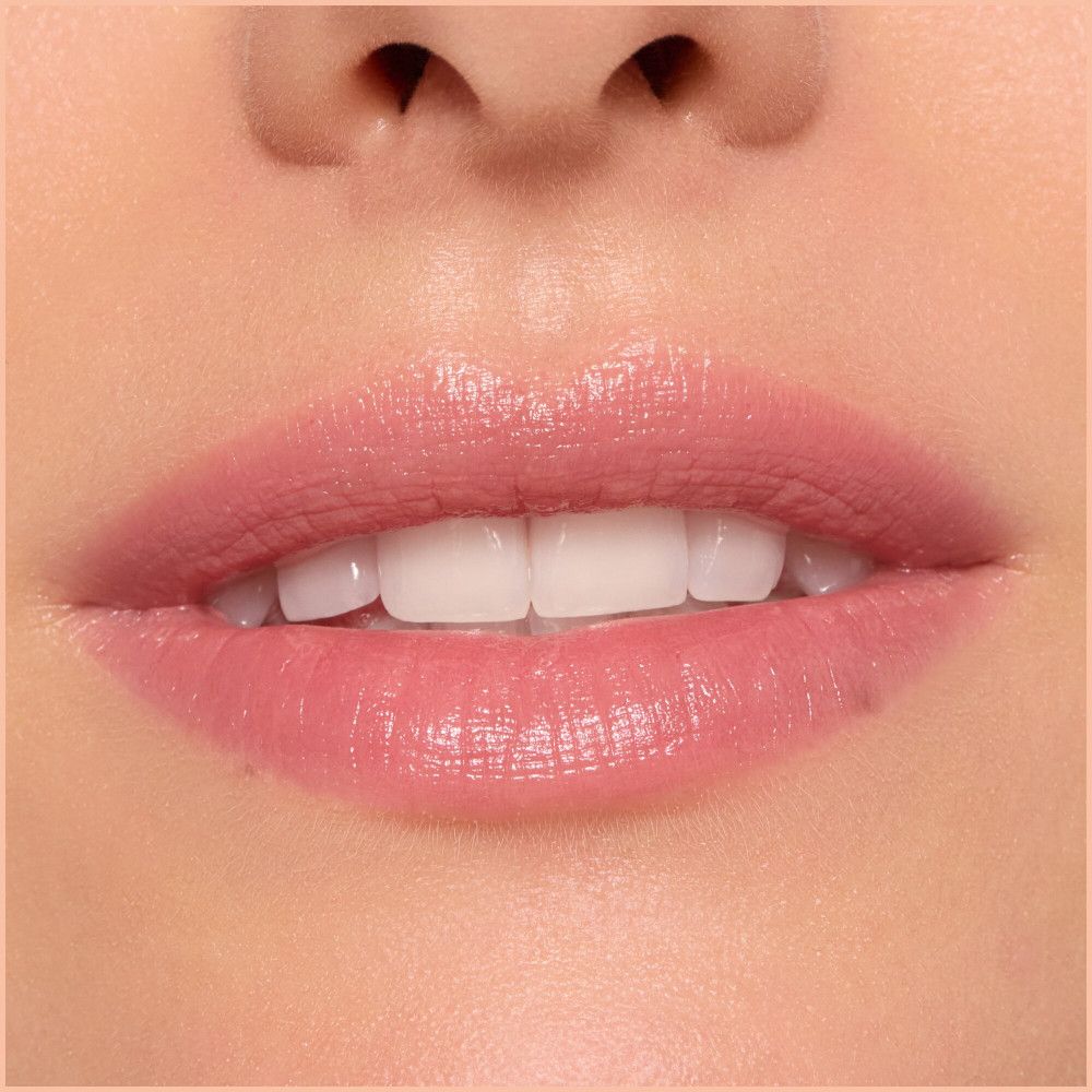 Gros plan sur des lèvres avec du baume à lèvres. Les lèvres sont brillantes et teintées de rose.