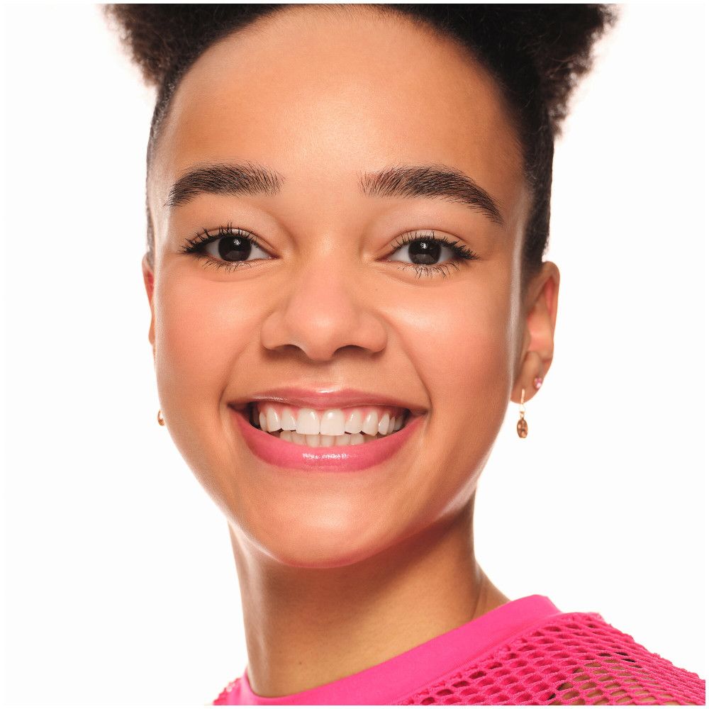 Gros plan d'une jeune fille souriante avec des lèvres roses. Elle porte un haut rose et a les cheveux foncés.