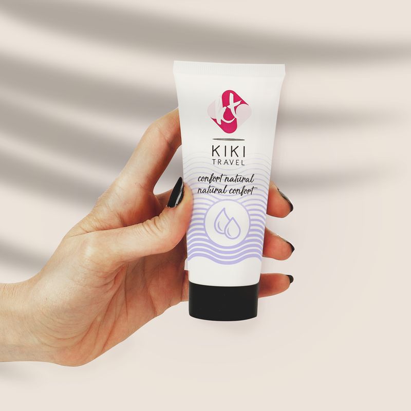 Une main tient un tube de gel lubrifiant Kiki Travel.