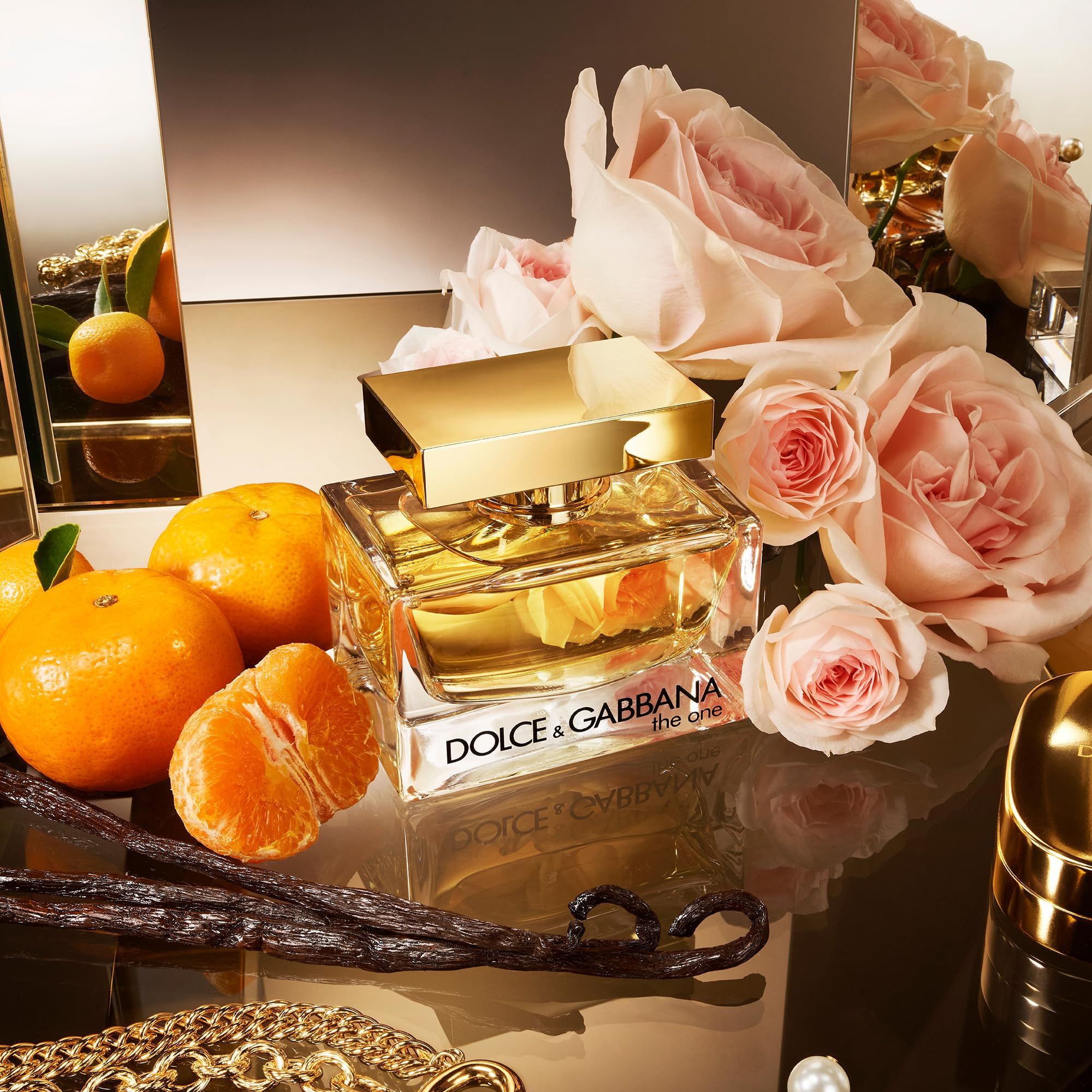 Parfumfles, gouden dop, omringd door rozen, mandarijnen en vanillestokjes. Weerspiegeling op glanzend oppervlak.