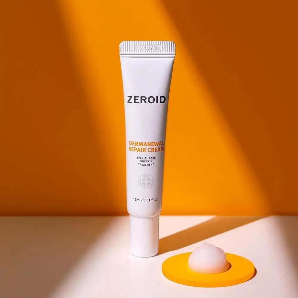 Tube blanc ZEROID Dermanewel Repair Cream avec crème sur dessous de plat jaune. 15ml / 0.51 fl oz.