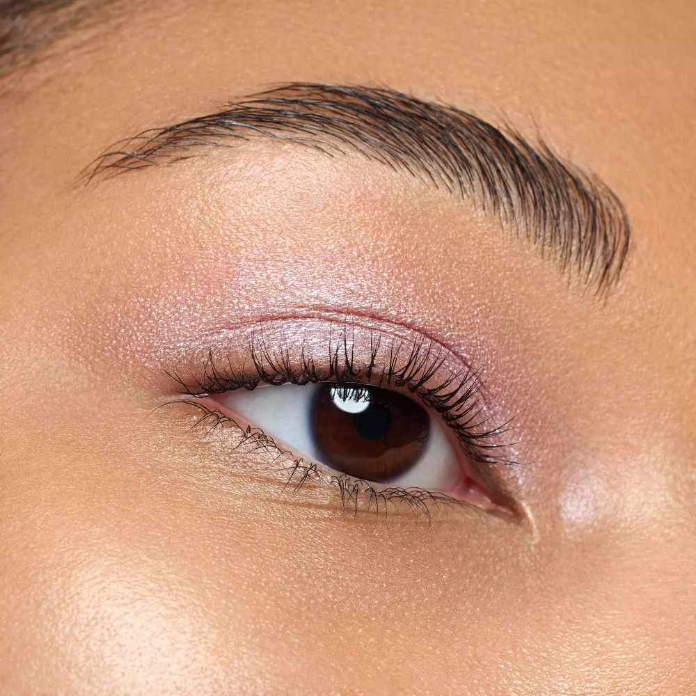 Gros plan d'un œil avec fard à paupières rose. Cils maquillés. Yeux marrons.