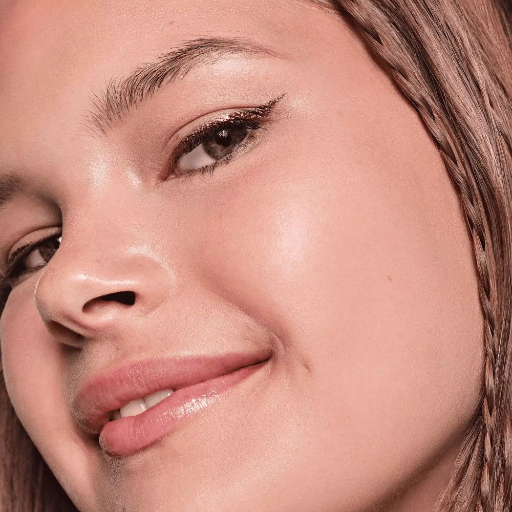 Gros plan d'une femme avec eyeliner métallique or rose. Regard vers la droite.