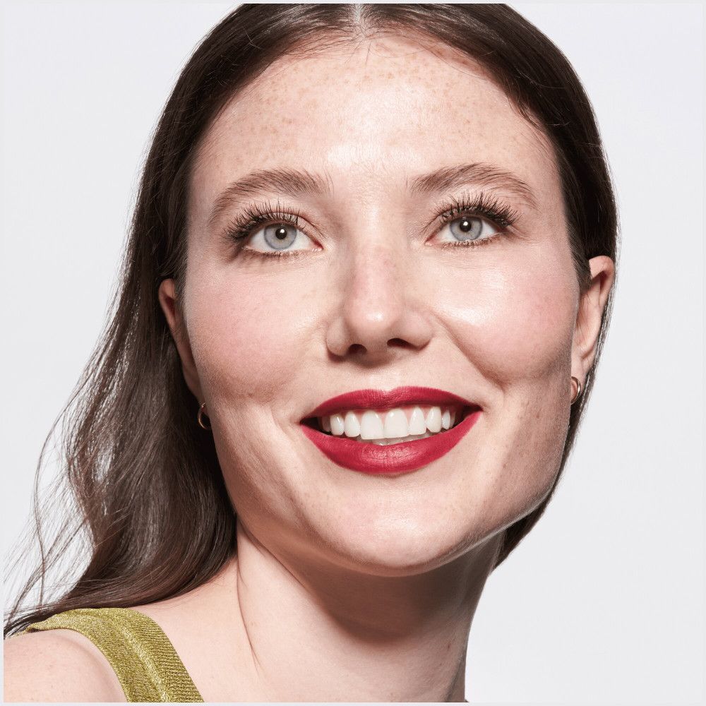 Portret van een vrouw met rode lippenstift. Ze lacht. Lichte huid, blauwe ogen.