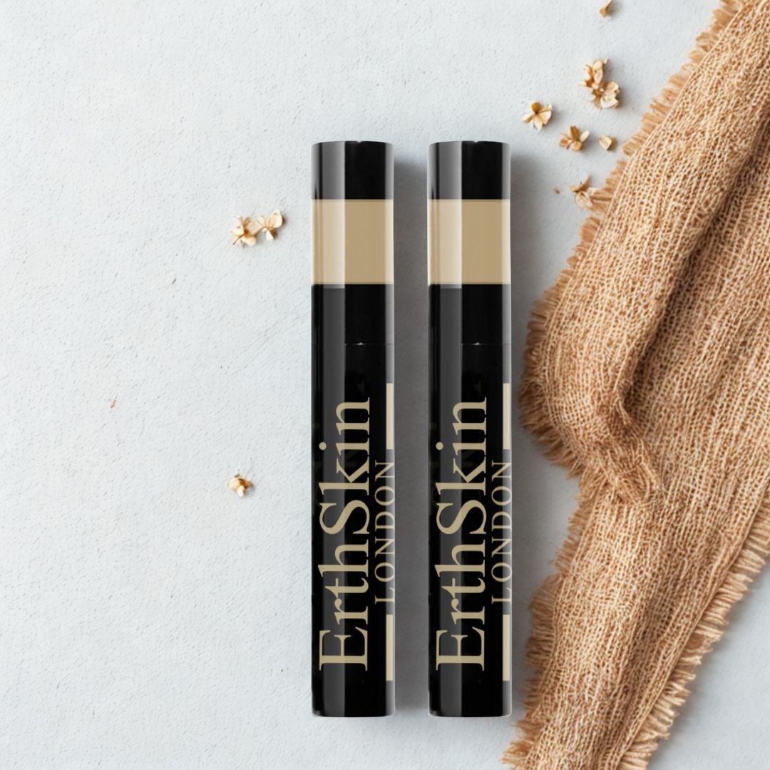 Deux tubes de mascara noirs avec texte doré. Inscription : ErthSkin London. Zone beige en haut. Sur fond clair avec tissu et fleurs.