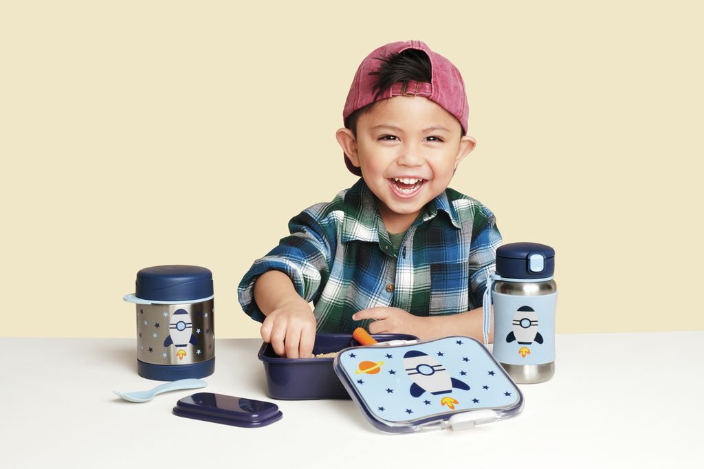 Kind met lunchset Raket. Bevat lunchbox, thermoskan, drinkfles, lepel. Raketontwerp op alle onderdelen. Kind lacht.