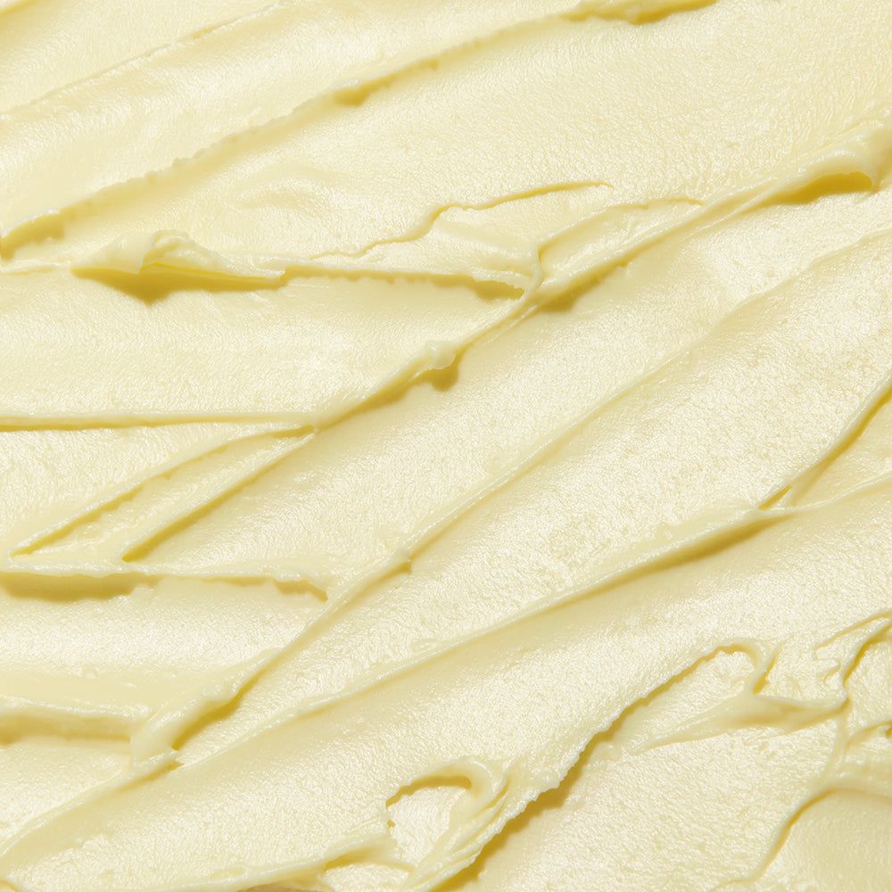 Gros plan de la texture crémeuse d'un baume jaune strié.
