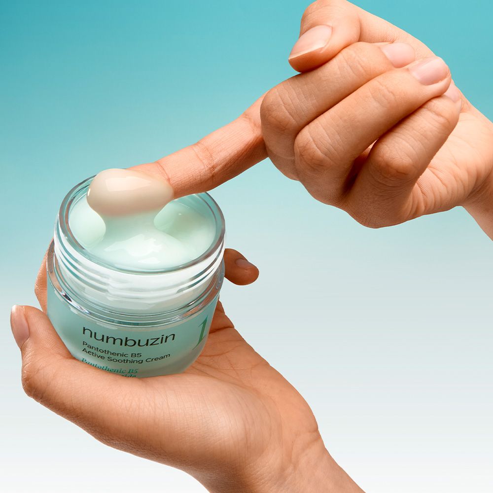 Une main prélève de la crème Numbuzin Pantothenic B5 d'un pot avec un doigt.