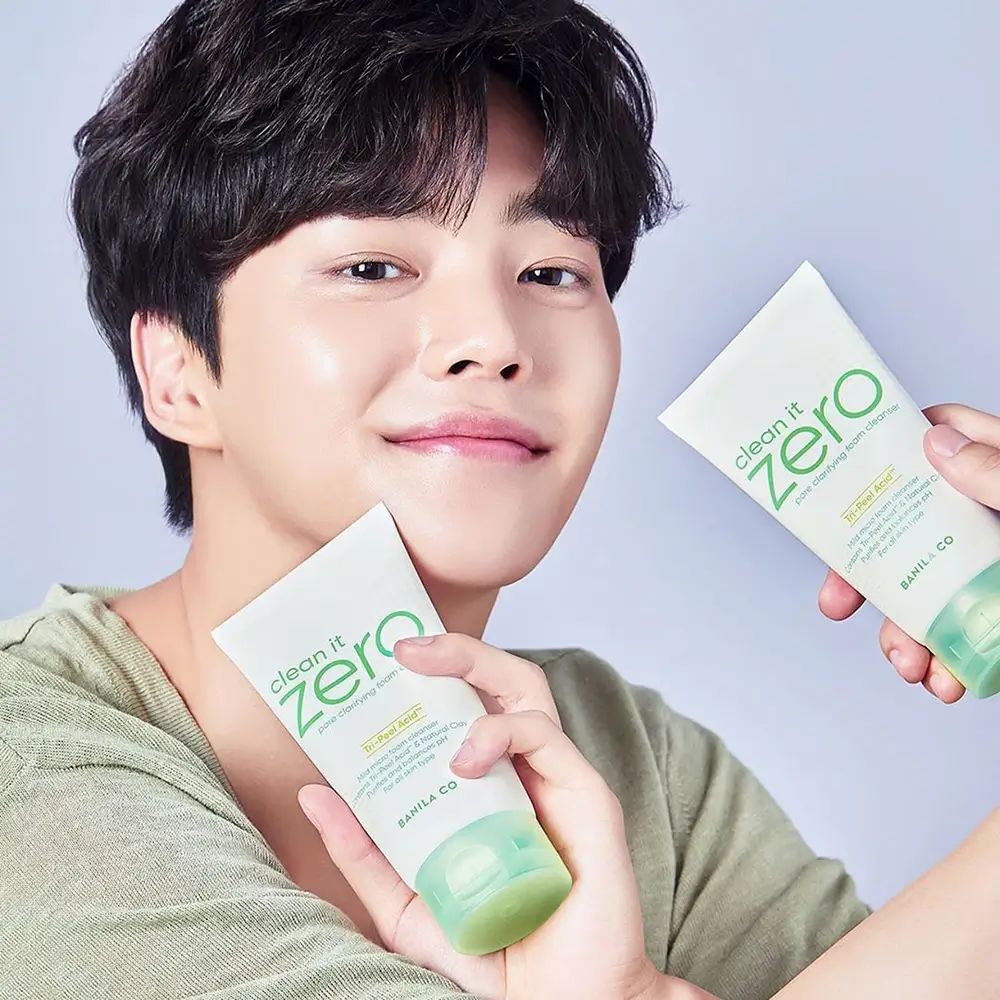 Homme tenant deux tubes. Les tubes affichent "clean it zero" et "BANILA CO". Les tubes sont blancs avec des accents verts.