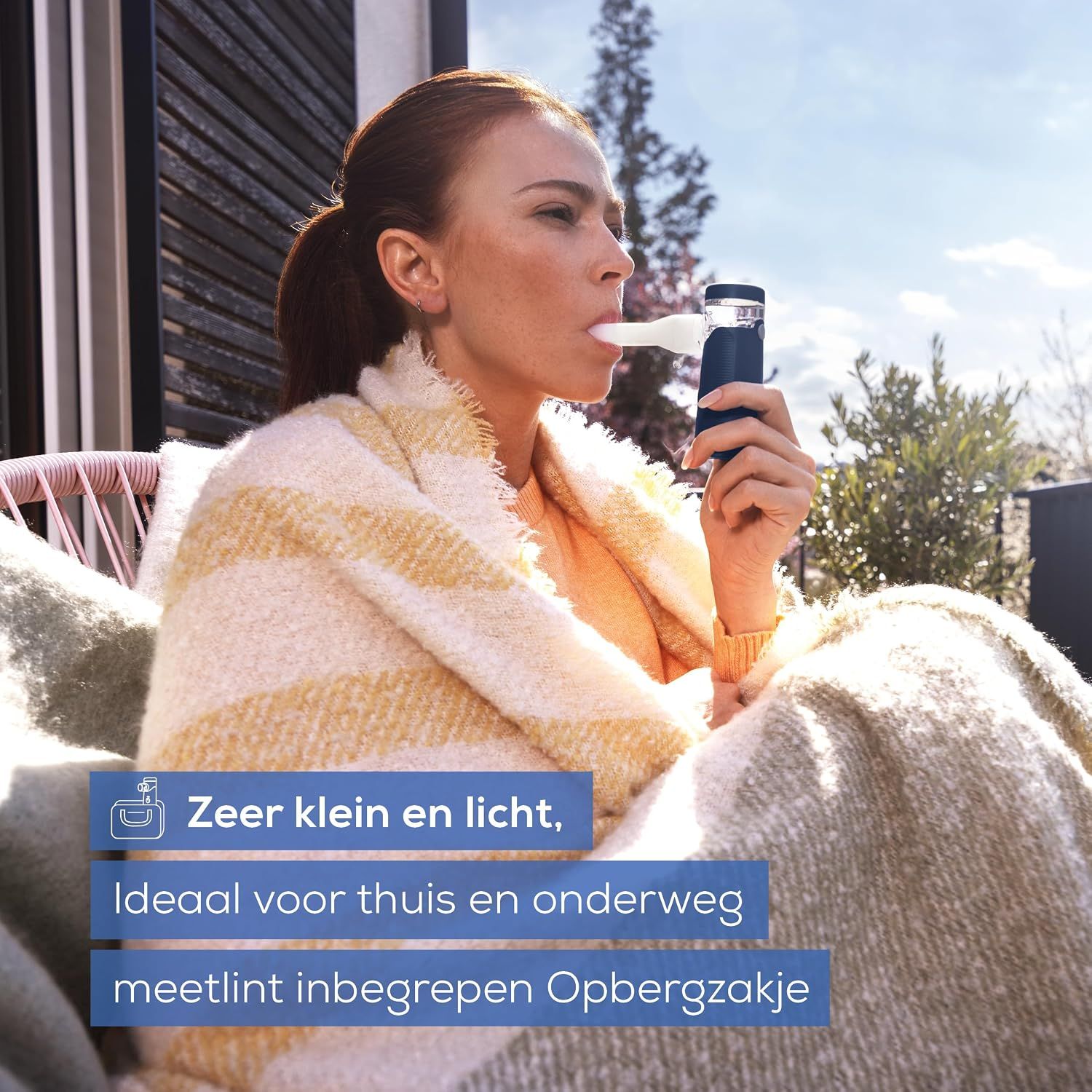Een vrouw gebruikt een blauwe inhalator met een wit mondstuk.