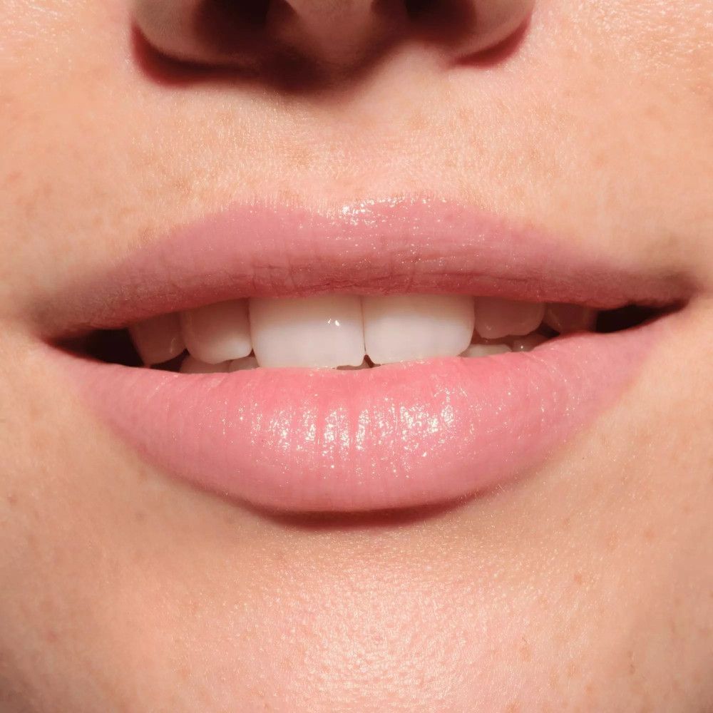 Close-up van geopende lippen. De lippen zijn bedekt met een roze balsem.