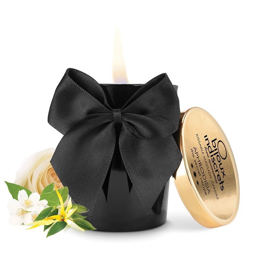 Bougie noire avec nœud, couvercle et fleurs. Inscription sur le couvercle. Flamme allumée. Bijoux Indiscrets.