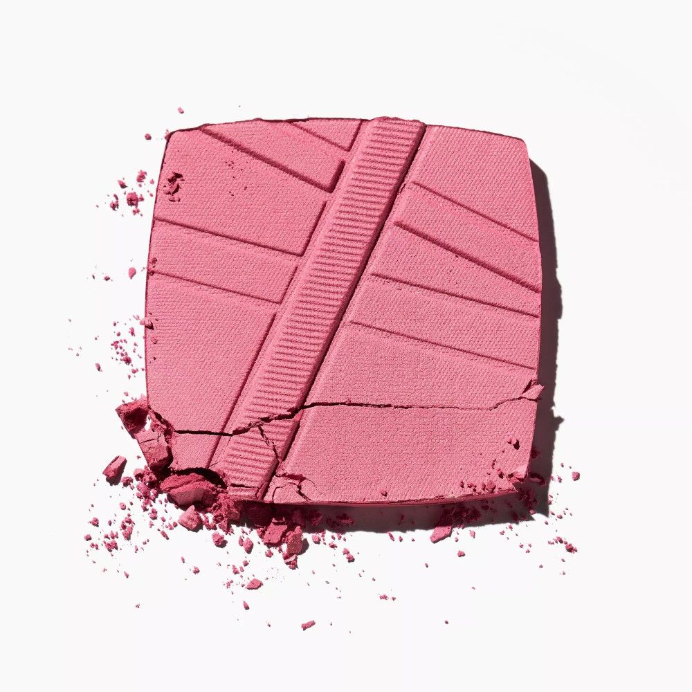 Rouge en poudre rose cassé avec motif en relief. Quelques particules de poudre sont éparpillées.