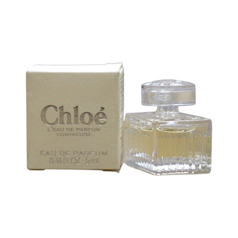 Kleine glazen fles met geribbeld ontwerp en doorzichtige dop, naast een klein crème doosje met 'Chloé' opschrift.