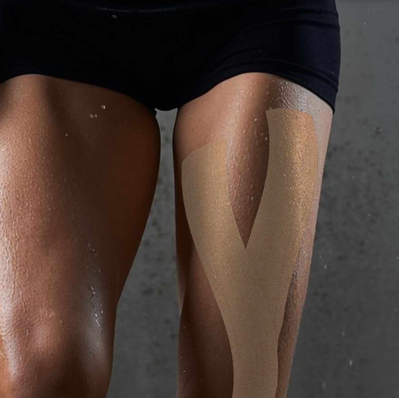 Dij van een persoon met beige kinesiotape. Tape aangebracht in V-vorm. Huid met waterdruppels.