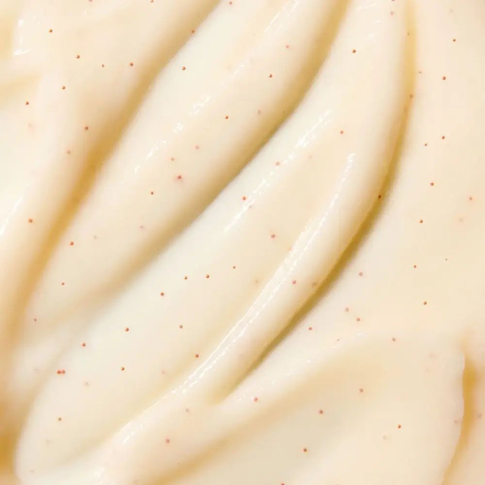 Gros plan de crème blanche crémeuse avec petites particules rouges. Texture lisse.