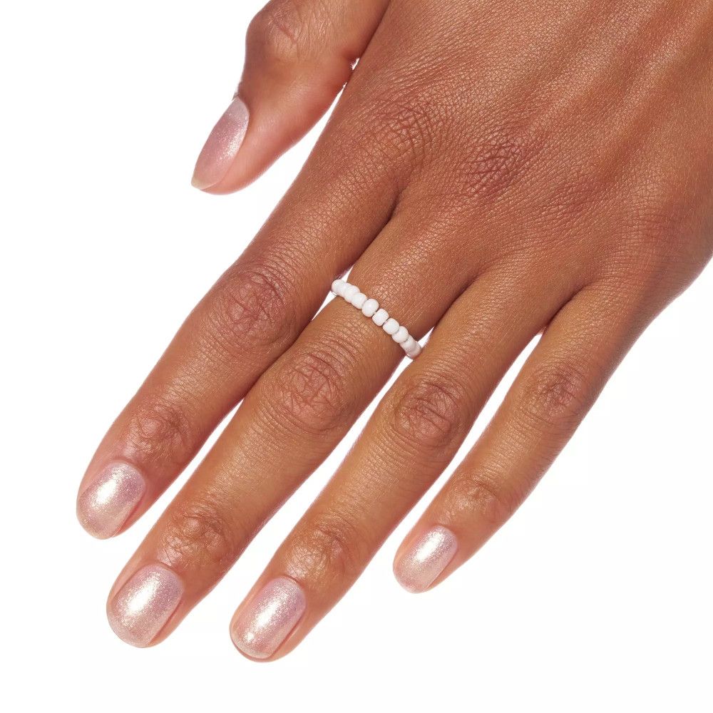 Main avec vernis à ongles rose scintillant et bague. Ongles vernis.