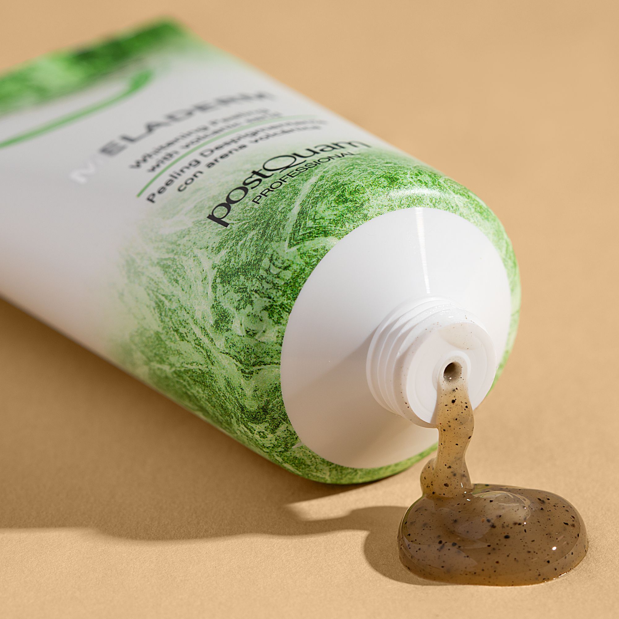 Witte tube, groene opdruk. Product komt uit de opening. Tekst: MELADERM, Whitening Peeling with volcanic sand, postQuam PROFESSIONAL.