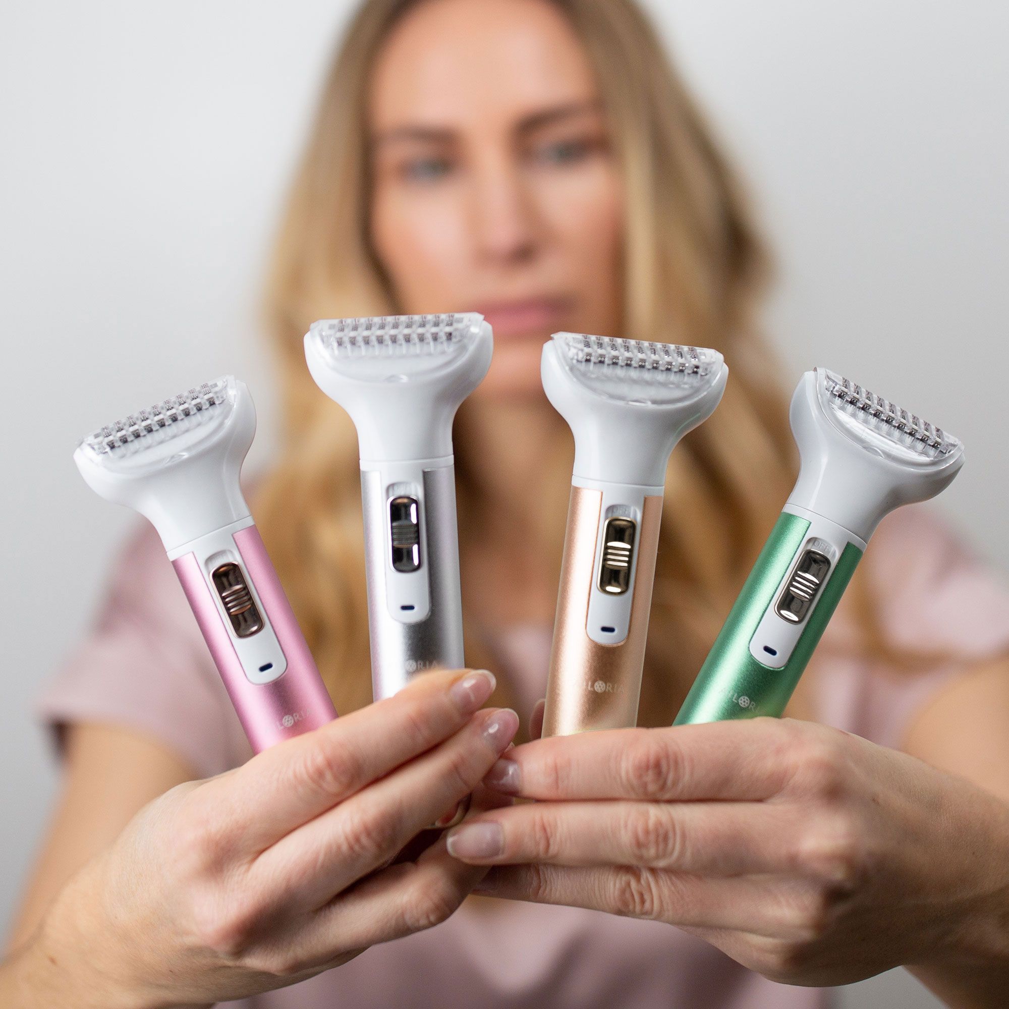 Quatre rasoirs corporels de couleurs différentes. Femme les tient.