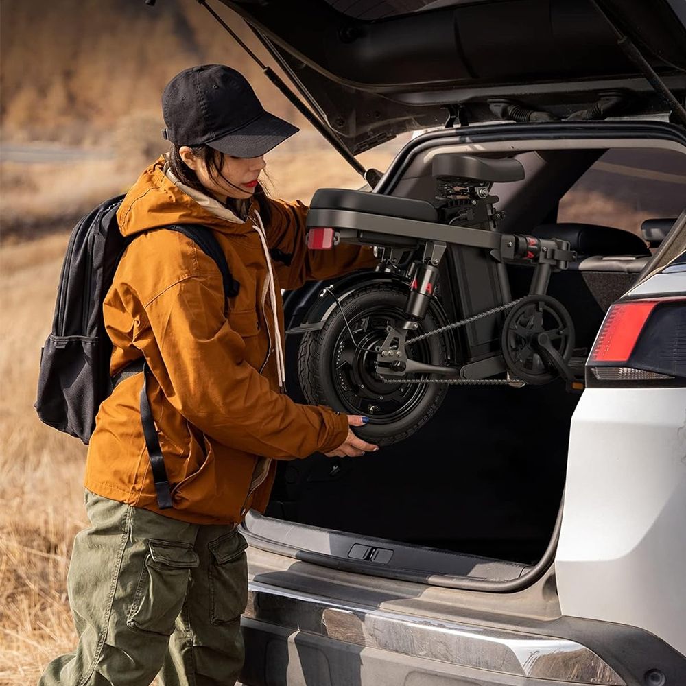 Vrouw haalt opvouwbare e-bike uit kofferbak. Zwarte fiets.