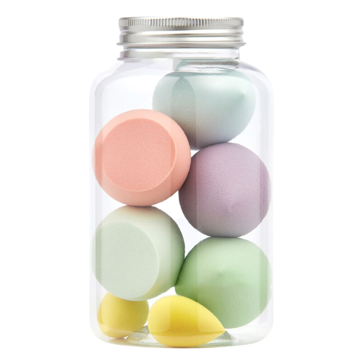 Een transparante pot met zilveren deksel, gevuld met zeven pastelkleurige make-upsponzen in verschillende vormen.