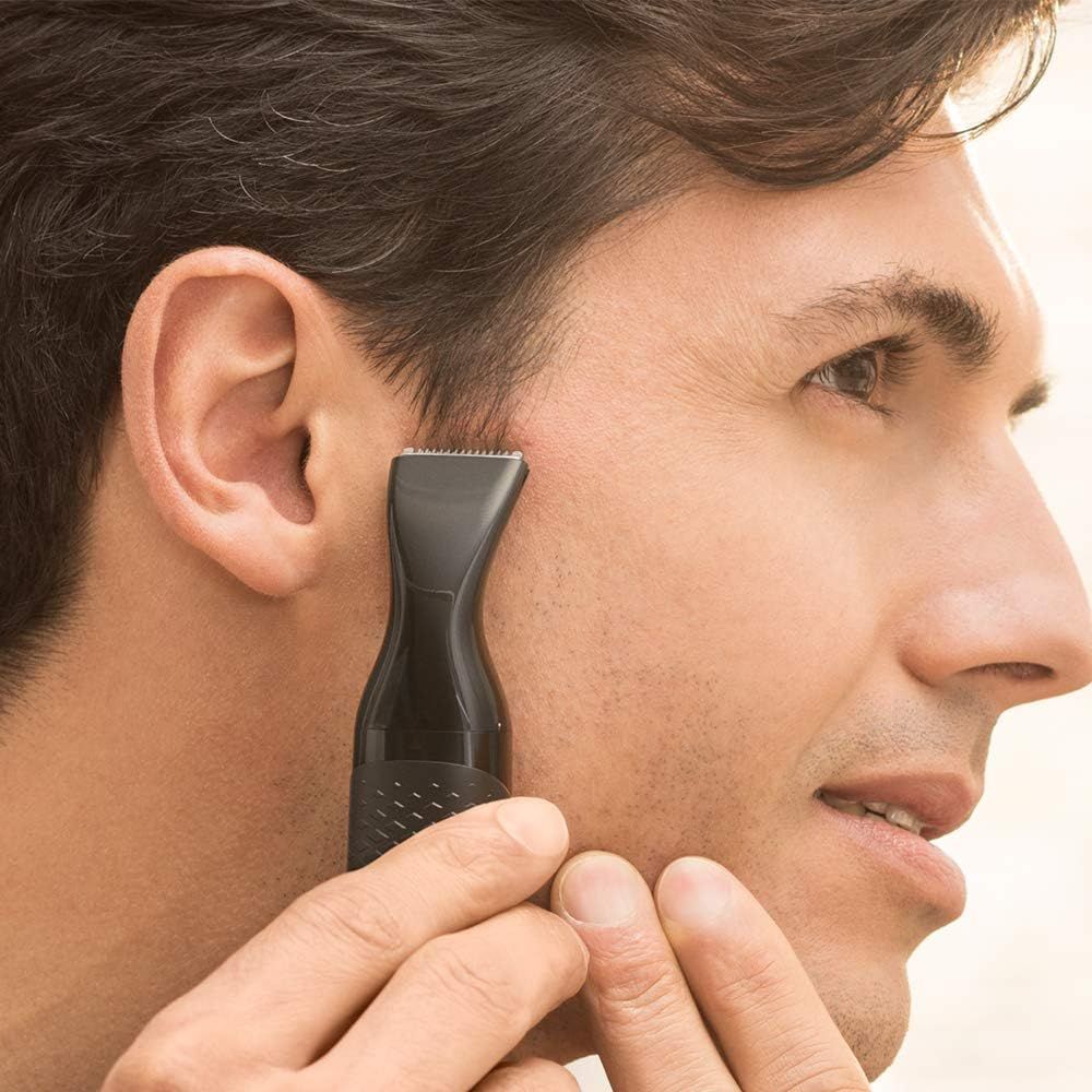 Man trimt met Philips trimmer. Zwart apparaat, trimdeel voor contouren.