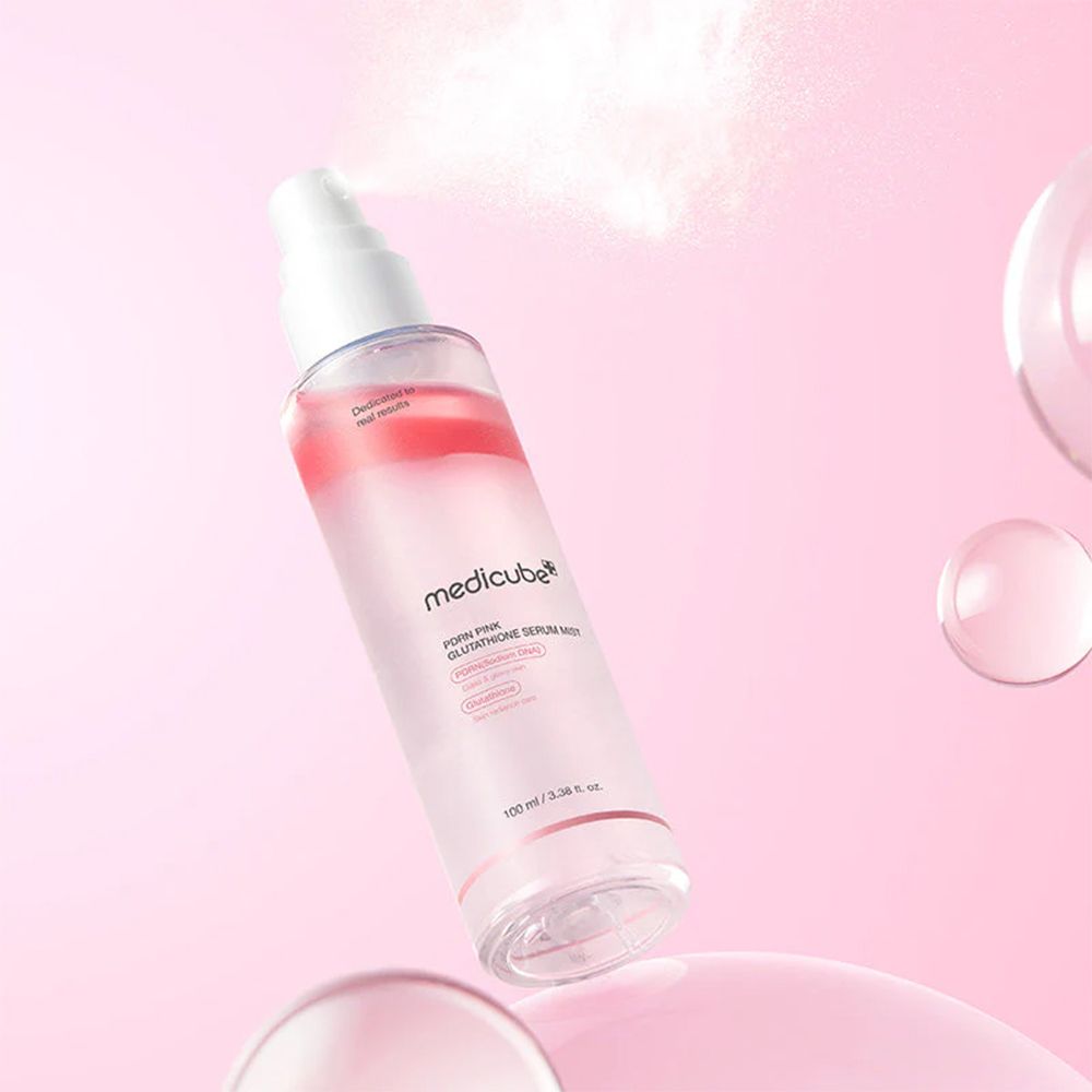 Medicube PDRN Pink Glutathione Serum Mist fles spuit mist. Zwevende glazen bollen en roze achtergrond.