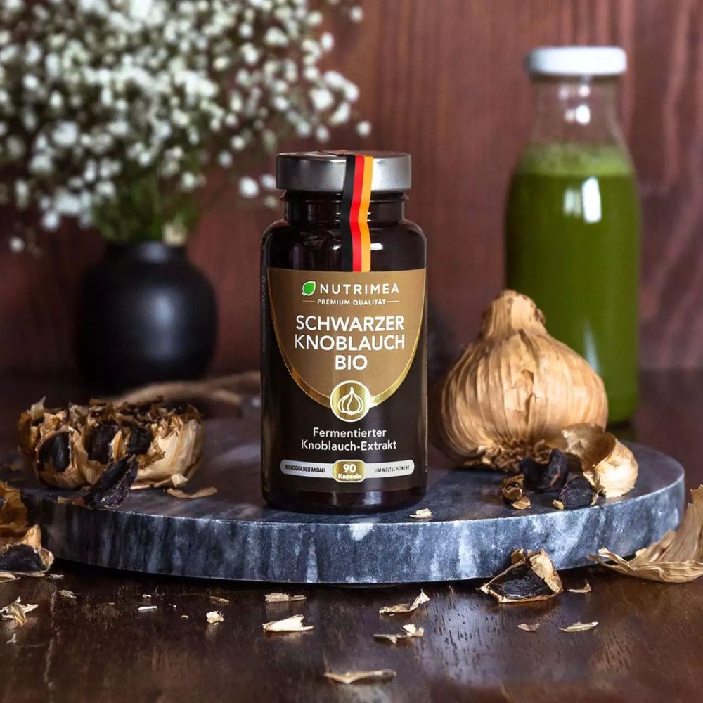 Bruine fles met Zwarte Knoflook BIO. Daarnaast knoflooktenen en groen sap.